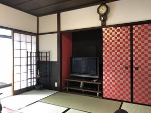 een kamer met een tv en een klok aan een muur bij Taisho Aburaya in Takayama