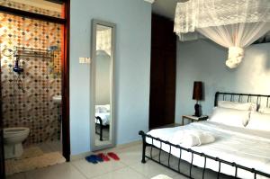 a bedroom with a bed and a bathroom with a toilet at Victoria Lake View Guesthouse & Safaris in Entebbe