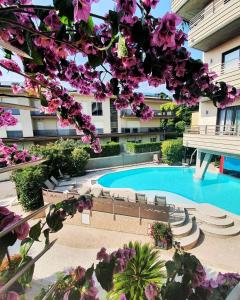 a building with a swimming pool and purple flowers at Hotel Desenzano in Desenzano del Garda