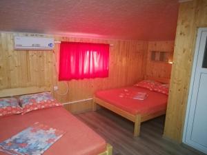 ein Zimmer mit zwei Betten und einem roten Fenster in der Unterkunft Vila Baciu in Tuzla