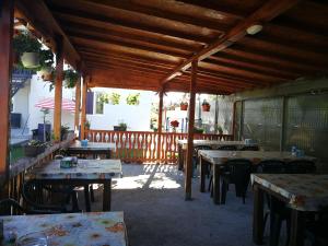 eine Terrasse mit Holztischen und Stühlen in einem Restaurant in der Unterkunft Vila Baciu in Tuzla
