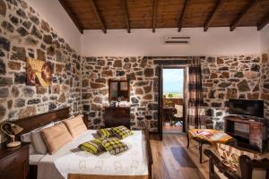 a bedroom with a bed and a stone wall at Balsamico Traditional Suites in Hersonissos