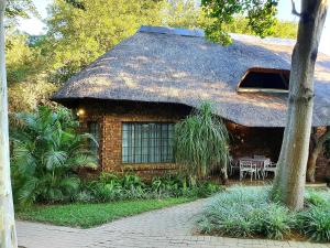 a house with a thatched roof with a patio at Shingalana Guest House in Hazyview