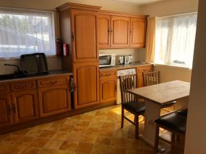 Una cocina con gabinetes de madera y una mesa con sillas. en Spacious home by the sea in Scalloway., en Scalloway 4 fotos más