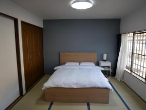 a bedroom with a large bed and a blue wall at Kanamori House in Takayama