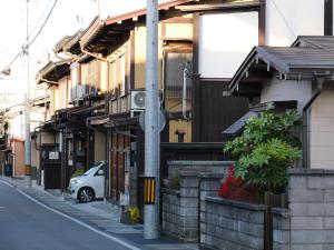 a street with buildings and a car parked on the street at Kanamori House in Takayama