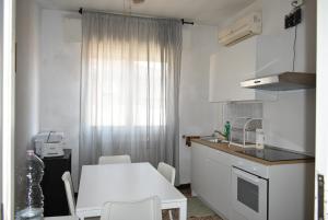 a white kitchen with a white table and chairs at Appartamento Daniele in Mestre