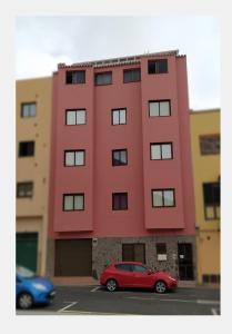 a red car parked in front of a building at apartamentos la villa 3 in San Sebastián de la Gomera