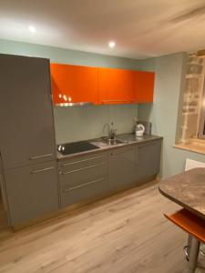 una cocina con armarios naranjas y grises y fregadero en Gite La Bastide, en Ornans