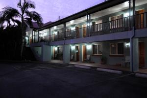 a night view of a building with a palm tree at Puffers Inn in Loganholme