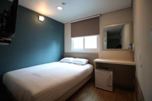 a small bedroom with a white bed and a blue wall at Dongdaemun Hwashin Hostel in Seoul