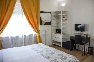a bedroom with a bed and a desk and a television at Aurelia Rooms in Verona