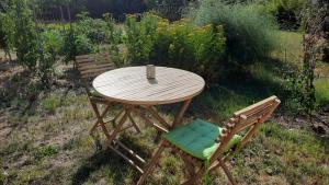 a wooden table and two chairs in a yard at Le grand souffle in Dolus d'Oléron