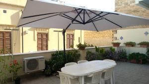 a white table and chairs under an umbrella at Sole di Trapani in Trapani