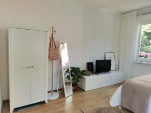 a white bedroom with a mirror and a television at Apartament w sąsiedztwie lasu 1800m od morza in Sopot