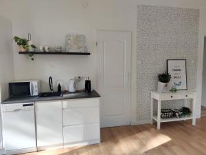 a white kitchen with a sink and a microwave at Apartament w sąsiedztwie lasu 1800m od morza in Sopot