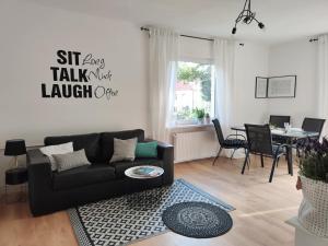 a living room with a black couch and a table at Apartament w sąsiedztwie lasu 1800m od morza in Sopot