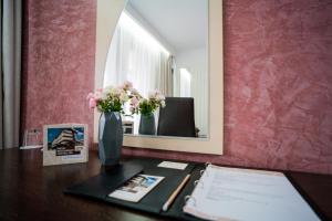 uma mesa com um vaso de flores e um espelho em Hotel Eden em Câmpulung Moldovenesc