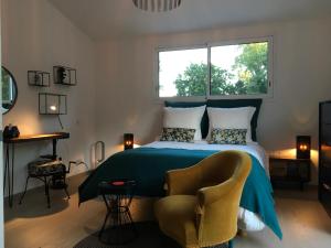 ein Schlafzimmer mit einem Bett, einem Stuhl und einem Fenster in der Unterkunft MADILOJE in Saint-Hilaire-de-Riez