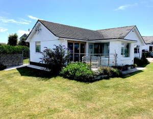 a white house with a porch and a yard at Beautiful coastal bungalow, Sennen, Porthcurno,sea in Penzance