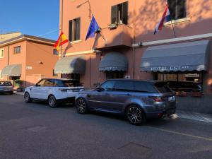 two cars parked in front of a building with flags at Hotel Est Piombino in Piombino
