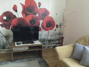 een woonkamer met een tv en rode papaver aan de muur bij Süti Nyaraló in Balatonmáriafürdő