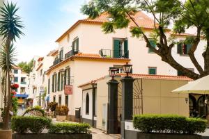 um edifício branco com uma árvore em frente em Amparo em Machico