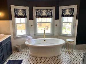 a bath tub in a bathroom with three windows at Slaymaker & Nichols Gastro House & Inn in Charlottetown