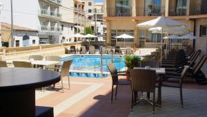 a hotel patio with tables and chairs and a pool at Hotel Iris in El Arenal