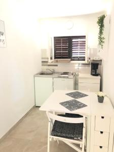 a white kitchen with a white table and a chair at Little house Ljubica in Kampor