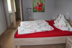 1 cama con manta roja y almohadas en Ferienhaus am Klosterhof, en Immendingen