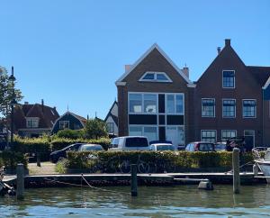 蒙尼肯丹的住宿－Who's Anton for you or two, Monnickendam near Amsterdam，码头前有车停放的房子