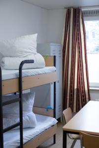 a dorm room with bunk beds and a table and a desk at Hostel & Monteurzimmer bei Hansezimmer in Hamburg