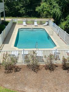 a large swimming pool with chairs and a fence at Condo w Pool near beaches, dining, shopping, etc in Gulf Shores