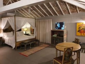 a bedroom with a canopy bed and a table and a tableablish at Pedra da Laguna Boutique Hotel SPA in Búzios