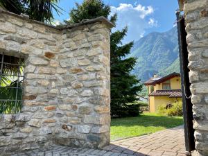 una entrada a una pared de piedra con montañas en el fondo en La Rosa Home, en Piuro