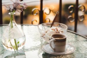 a glass table with a cup of coffee and a vase with flowers at Sisiotisa in Argostoli