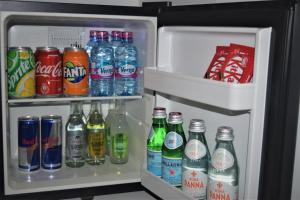 an open refrigerator filled with lots of soda and drinks at The Alima Suites in Accra