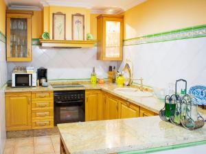 cocina con paredes amarillas y armarios de madera en Belvilla by OYO Preciosa casa en Sevilla, en Sevilla