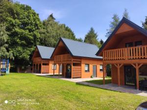 un par de casas de troncos en un parque en LEŚNA OSTOJA en Rewal