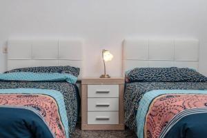 1 dormitorio con 2 camas y mesita de noche con lámpara en Casa Yamile, en Tarajalejo