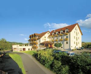 un gran edificio con coches estacionados al lado de una carretera en Panorama-Hotel am See en Neunburg vorm Wald