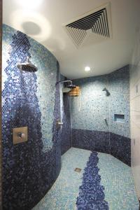 uma casa de banho com um chuveiro com mosaicos azuis em Panorama-Hotel am See em Neunburg vorm Wald
