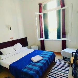 een slaapkamer met een blauw en wit bed en een raam bij Transit Alexandria Hostel in Alexandrië
