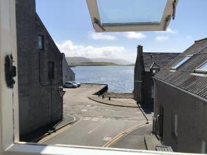Una vista desde una ventana de una calle junto a un cuerpo de agua. en Spacious home by the sea in Scalloway., en Scalloway