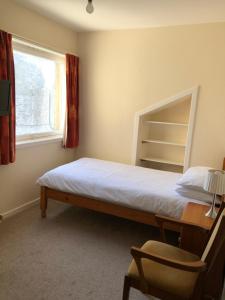 Un dormitorio con una cama y un escritorio y una ventana. en Spacious home by the sea in Scalloway., en Scalloway