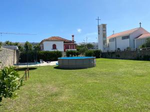 un gran patio con una cama elástica en el césped en Beach House with Swimming Pool, en Vila do Conde