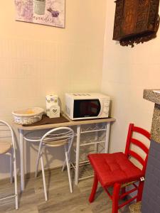 een tafel met een magnetron en een rode stoel bij casa la valle in San Fedele Intelvi