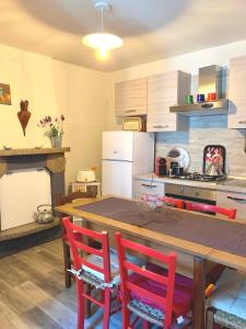 a kitchen with a wooden table and red chairs at casa la valle in San Fedele Intelvi