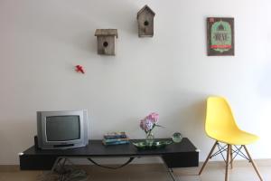 a tv sitting on a table next to a yellow chair at Casinha da Andorinha - Ericeira in Ericeira